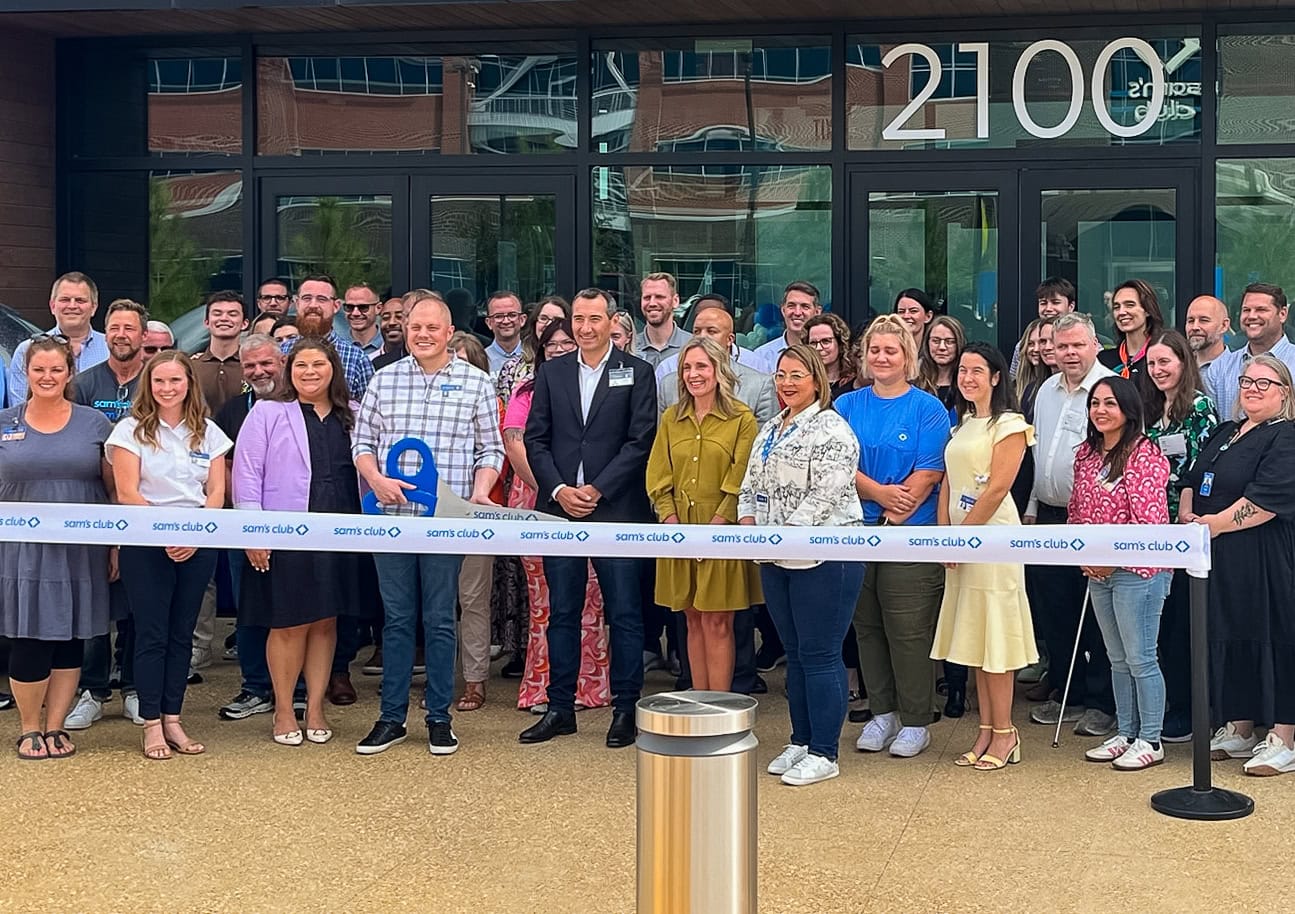 Bentonville Mayor Stephanie Orman and A group of people stand behind a ribbon at a ribbon cutting event for Sam's clubhouse in Bentonville, Arkansas